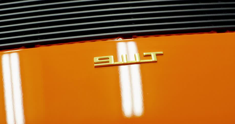 Light reflects on the paint and logo of a Porsche 911 T