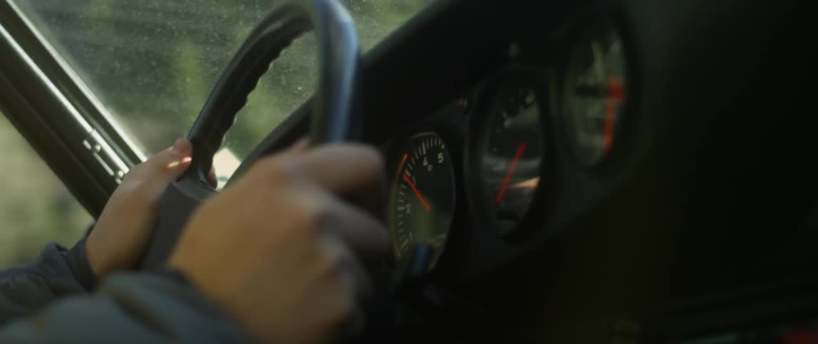 Hands rest on a steering wheel in a moving car