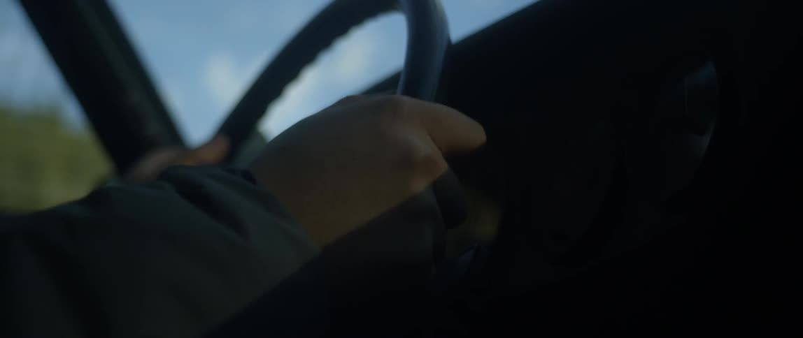 A person holds a steering wheel as they drive a vehicle