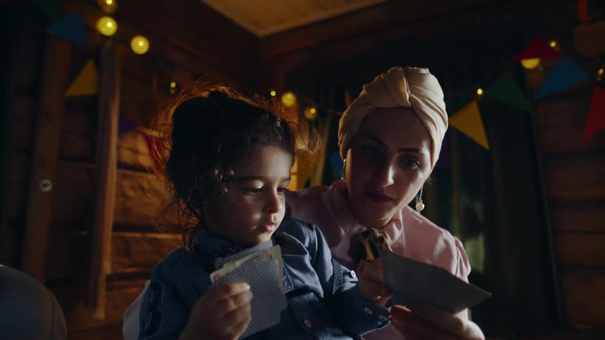 A mother and young daughter play cards at a party