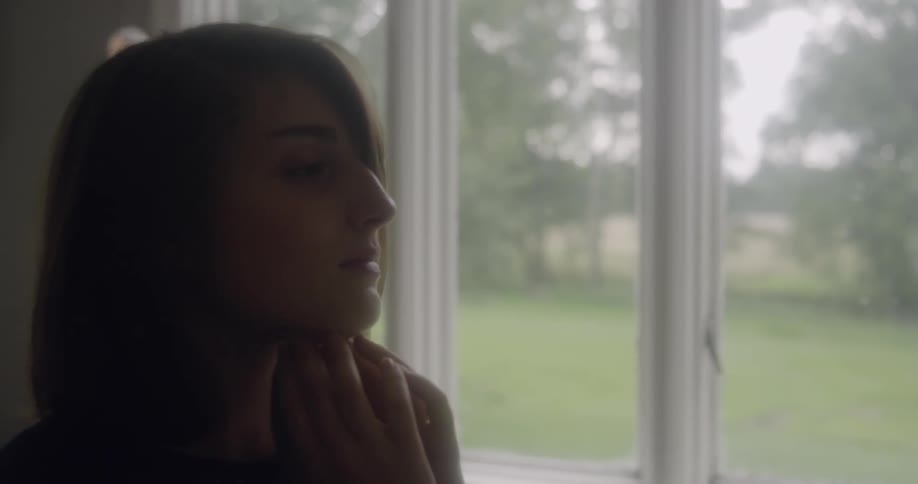 A woman massages her neck and touches her face
