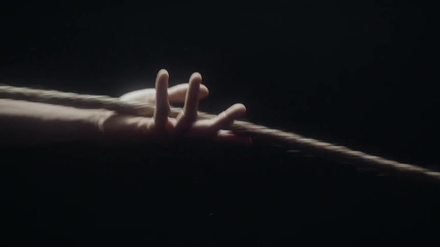 Person's hand slides down a rope until it lets go