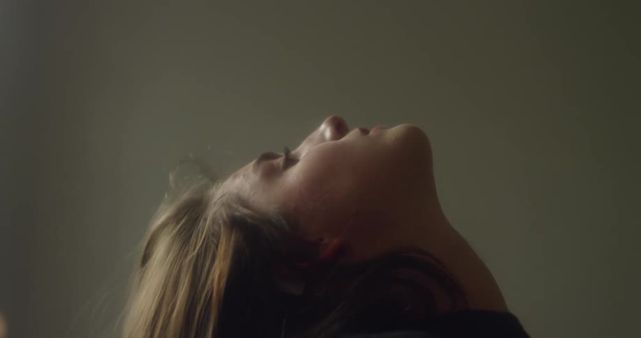 A woman sits up slowly on a bed