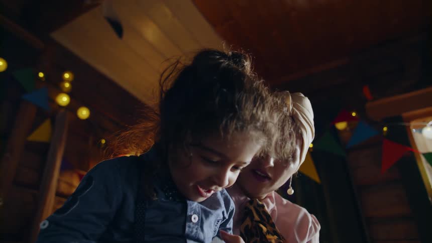 A mother and young daughter play cards at a party