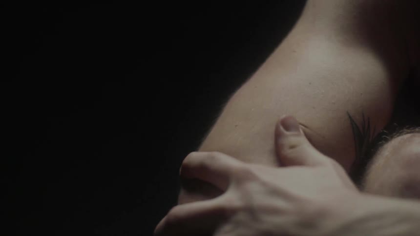 The man leans over his knees in the dark