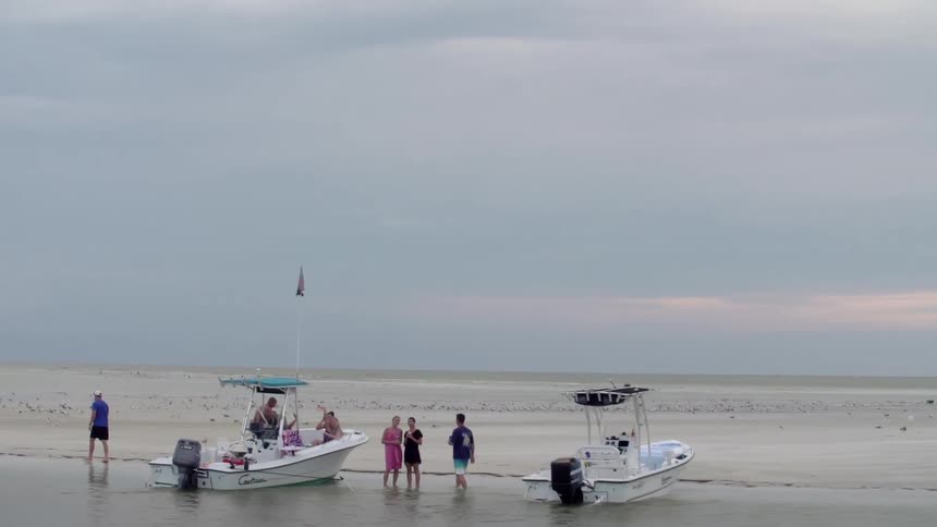 People gather around boats on a beach