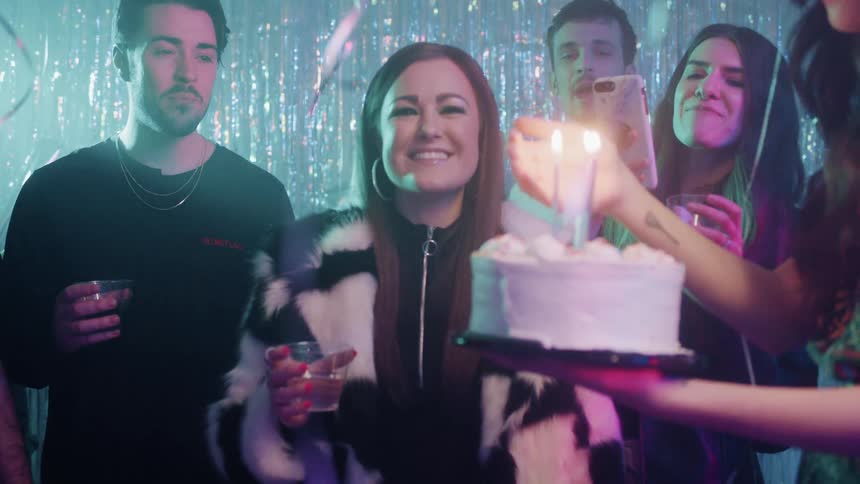 The woman blows the candles out on a birthday cake