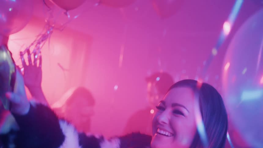 Woman in an black and white coat smiles at a party