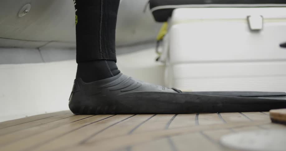A scuba diver wears flippers in a boat
