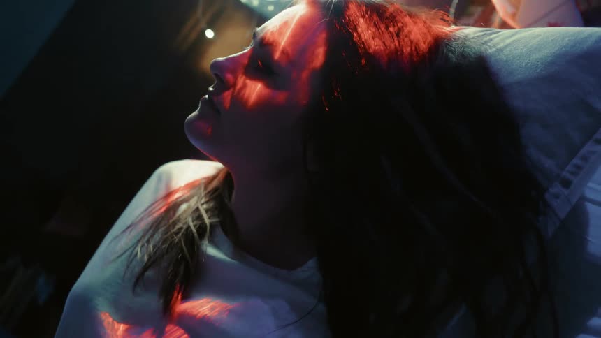 Lights shine on a woman while she lies on a pillow