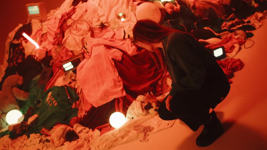 A woman crouches in front of a pile of random objects