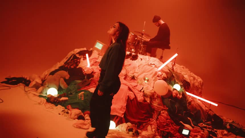 A woman walks in front of a pile of random objects