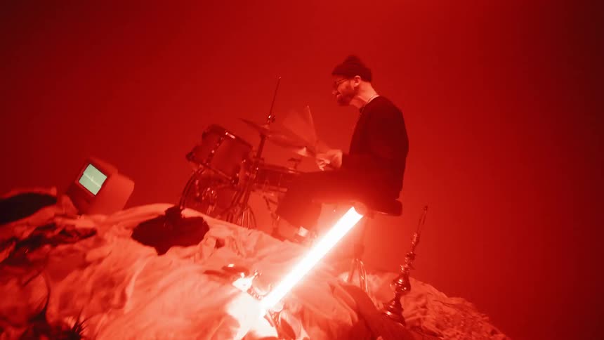 The man is playing drums on a pile of clothes