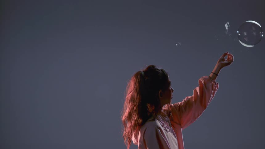 A woman pops a floating bubble