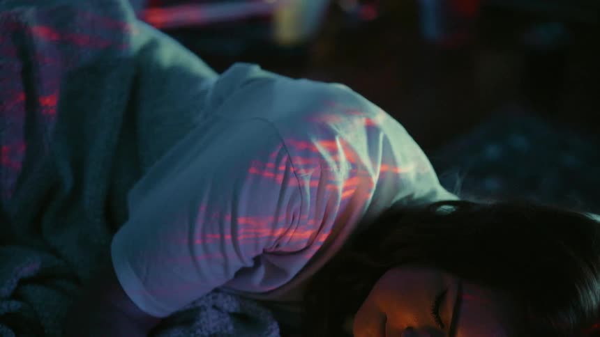 A woman sleeping in bed as a red light flashes