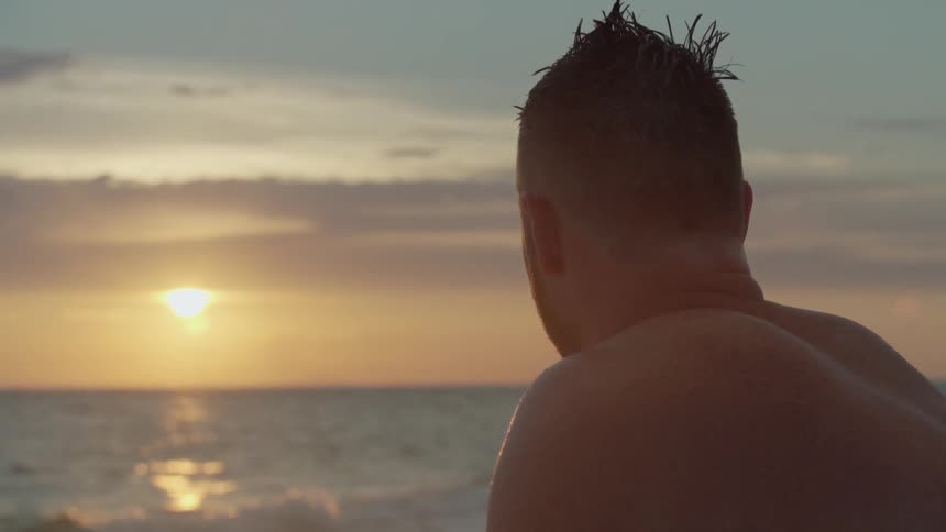 A man sits and watches the sunset at the beach