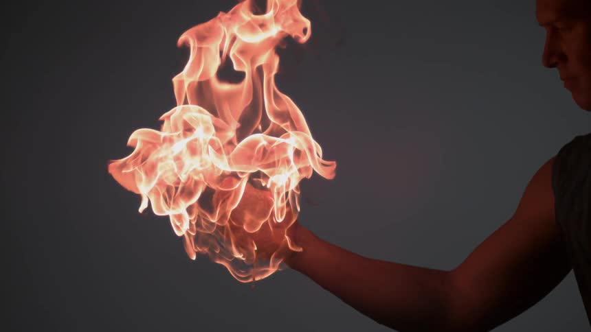 The man looks on as his hand is engulfed in flames