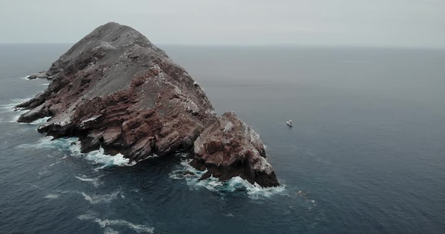 Ocean waves crash into a large rock in the sea