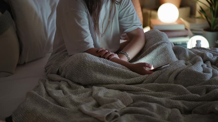 A woman sits in bed on a sunny day