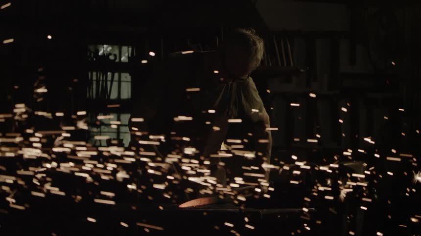 Sparks fly around a blacksmith at work