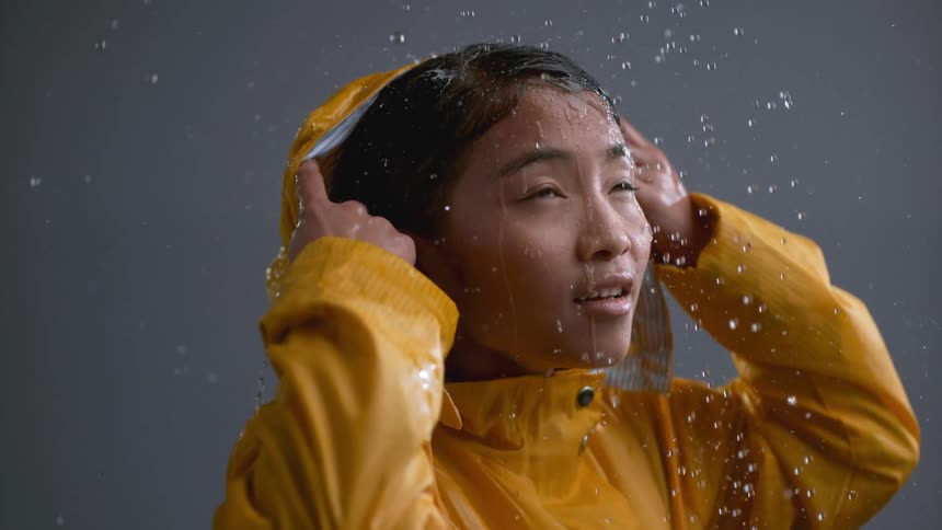 A girl removes the hood of her raincoat in the rain