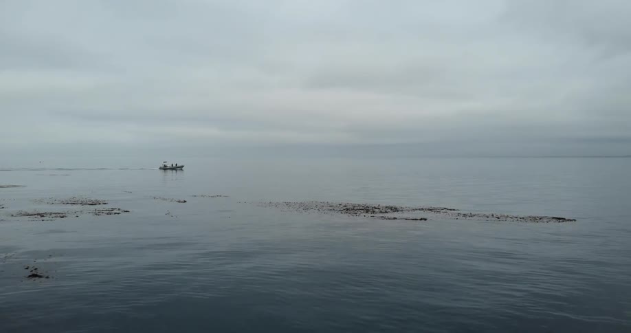 A boat floats on an ocean on a cloudy day