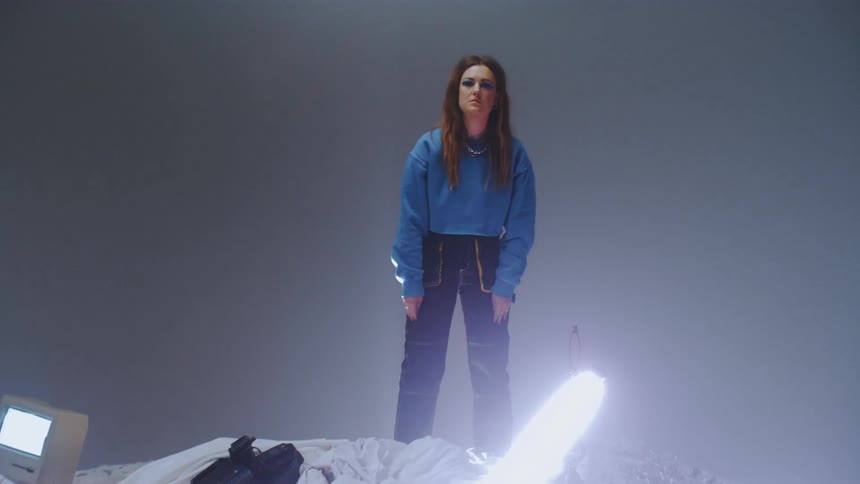 A woman stands on top of a pile of random objects