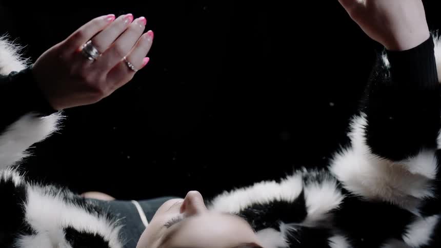A woman lifts her arms in a fur coat