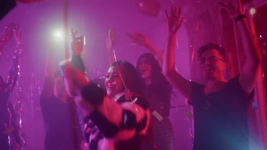 People dance at a party with balloons and confetti