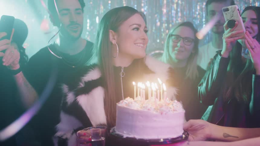 Woman blows out candles on a birthday cake