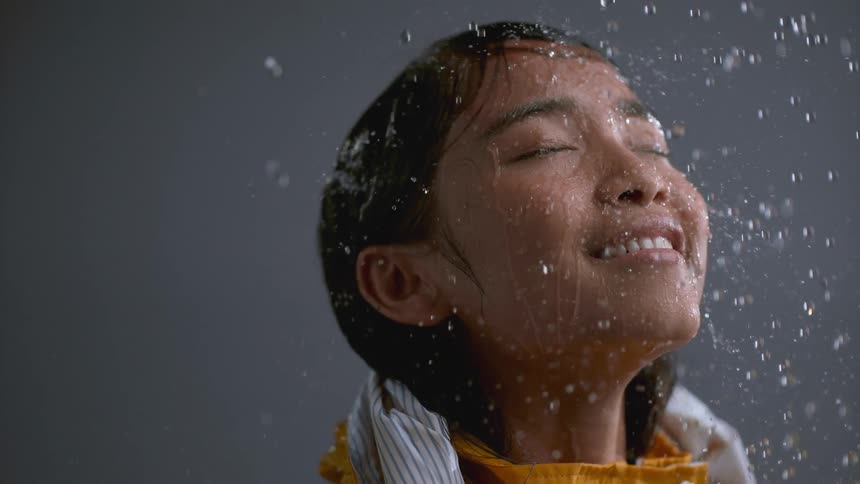 A girl smiles while rain falls on her face