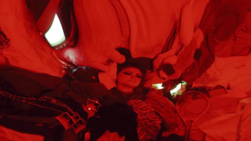 A woman lies on top of a pile of random objects