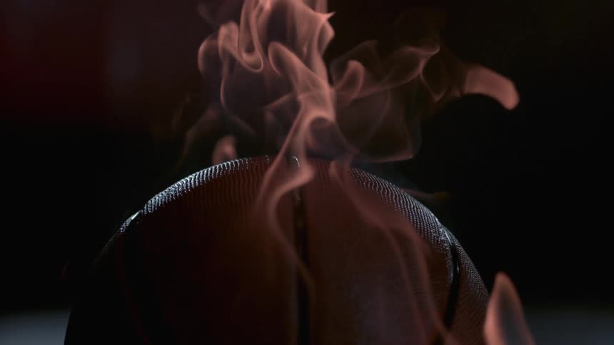 A basketball on fire in a dark room