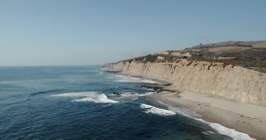 The boat travels past the shore with rough waves