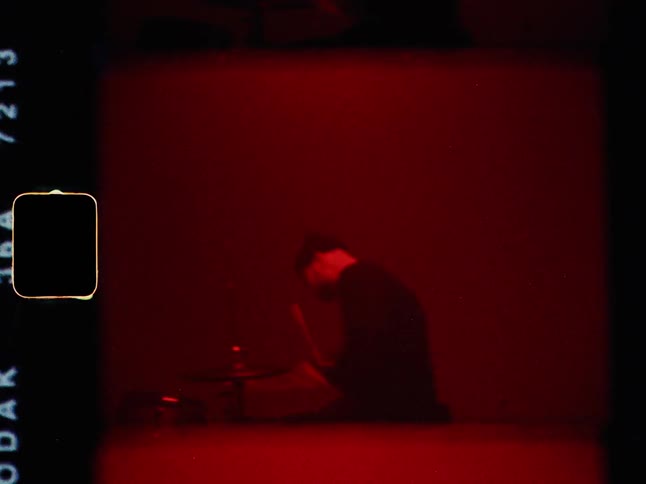 The man is playing his drums fast in the red room