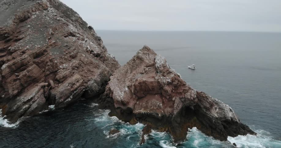 Ocean waves crash into a large rock in the sea