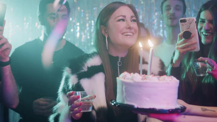 The woman blows out the candles as the others cheer