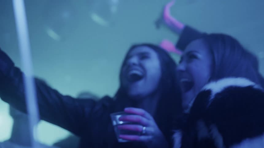 Many men and women jump and party in a room with blue light