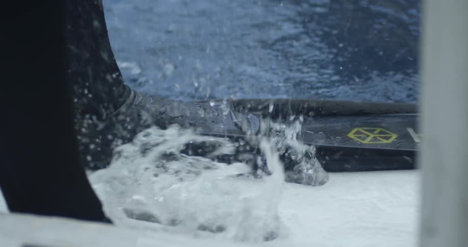 Person wearing a flipper stands at the edge of splashing water