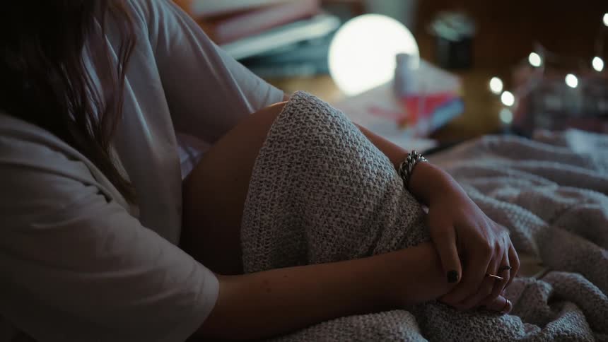 A woman sits up in bed