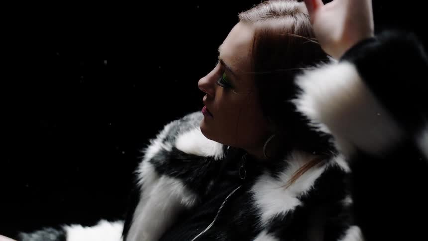 A woman lifts her arms in a fur coat