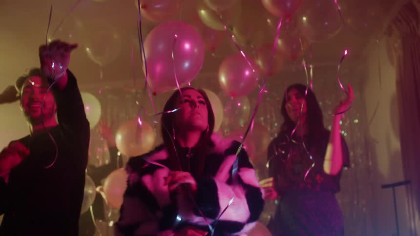 People dance at a party with balloons