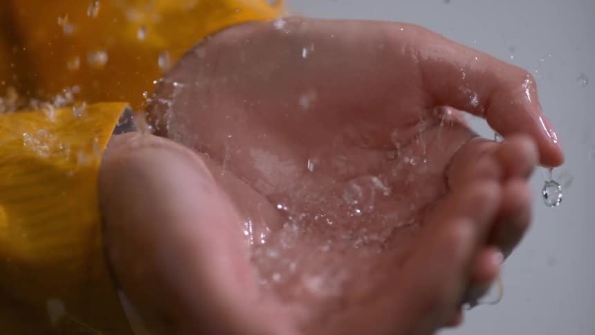 The water crashes down on the person's hands