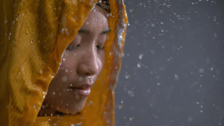 The woman stands in the rain wearing a raincoat