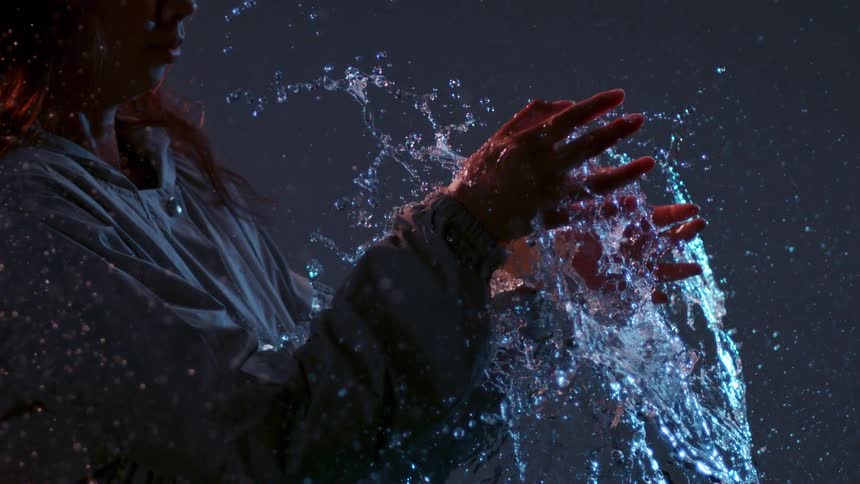 A woman holds a water balloon as it pops