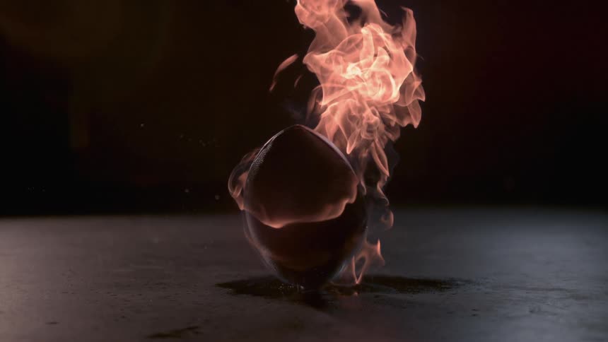 The football is spinning on the ground on fire