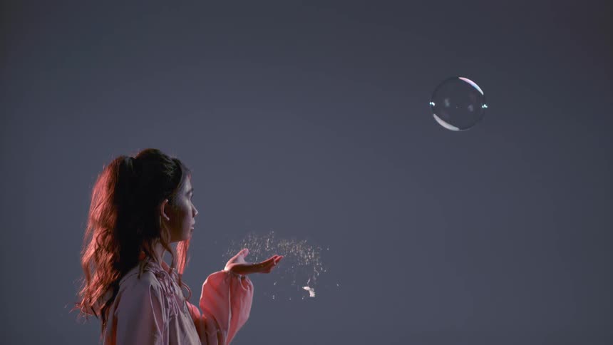 A woman pops a floating bubble