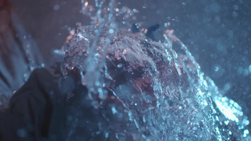 The person pops a balloon splashing water everywhere