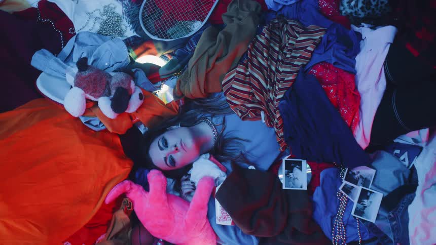 A woman lies on a pile of random objects