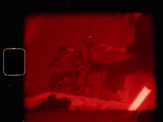 The man plays the drums under the flashing red lights